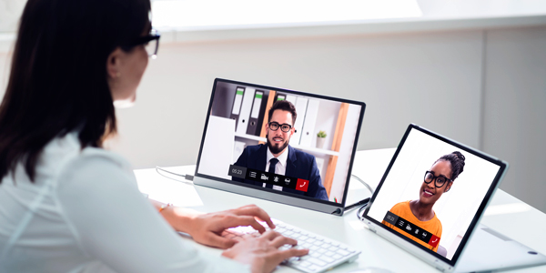 Video conference on two tablets, with one person typing on the keyboard.