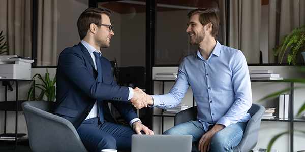 Person smiling while shaking advisors hand