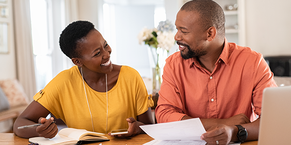 Husband and wife smiling while reviewing finances